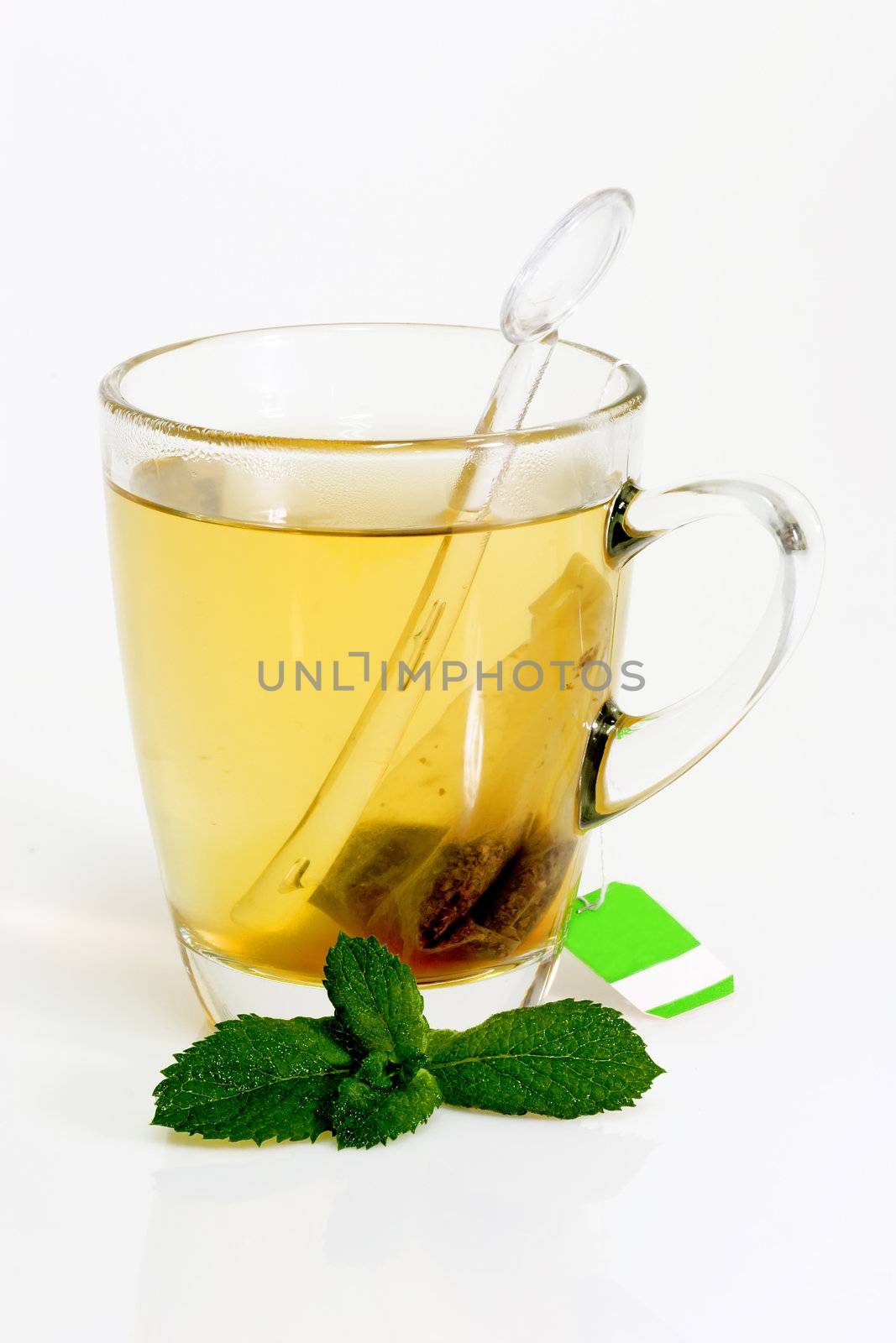 Glass of hot tea with peppermint on bright background