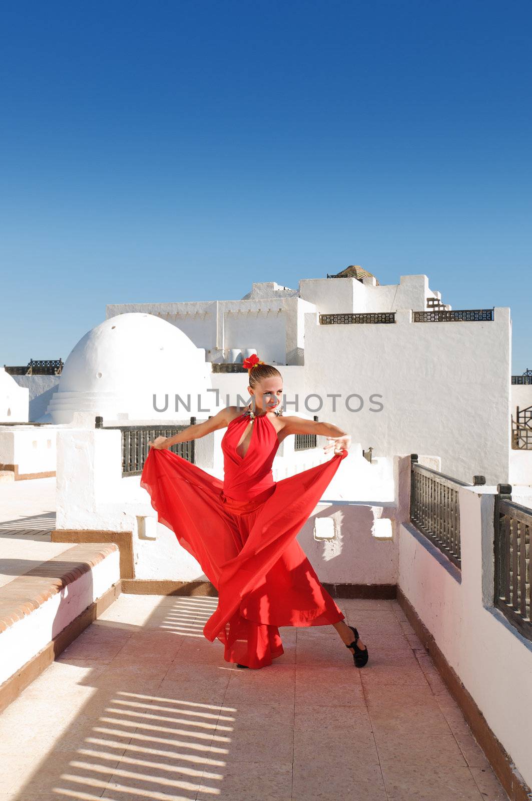 Attractive flamenco dancer wearing traditional red dress with flower in her hair