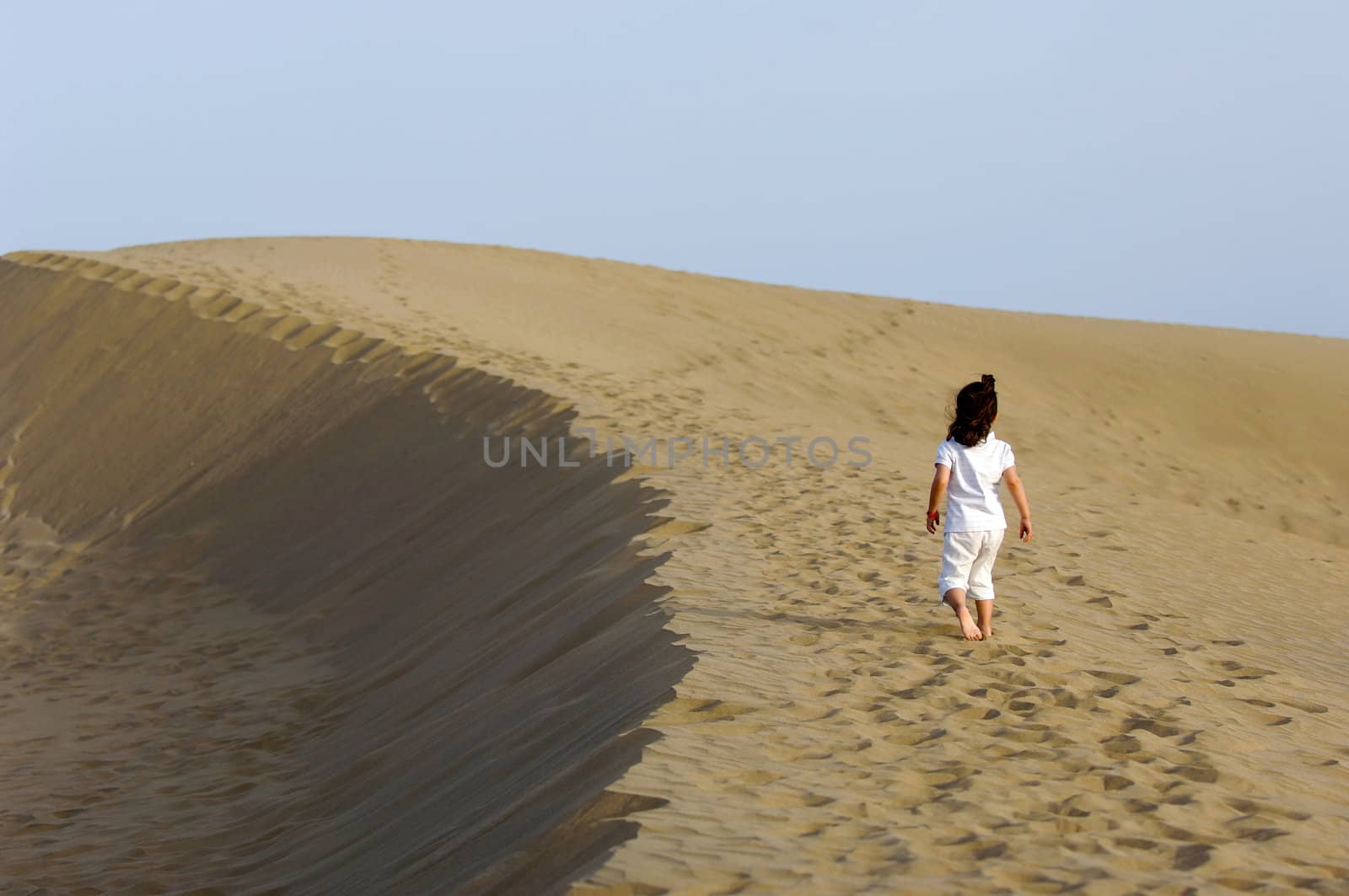 A child is walking all alone in the desert