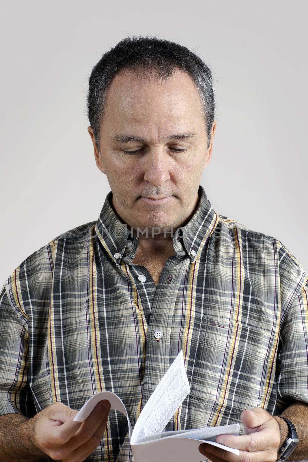 Middle-aged man reading an instruction manual looking puzzled.