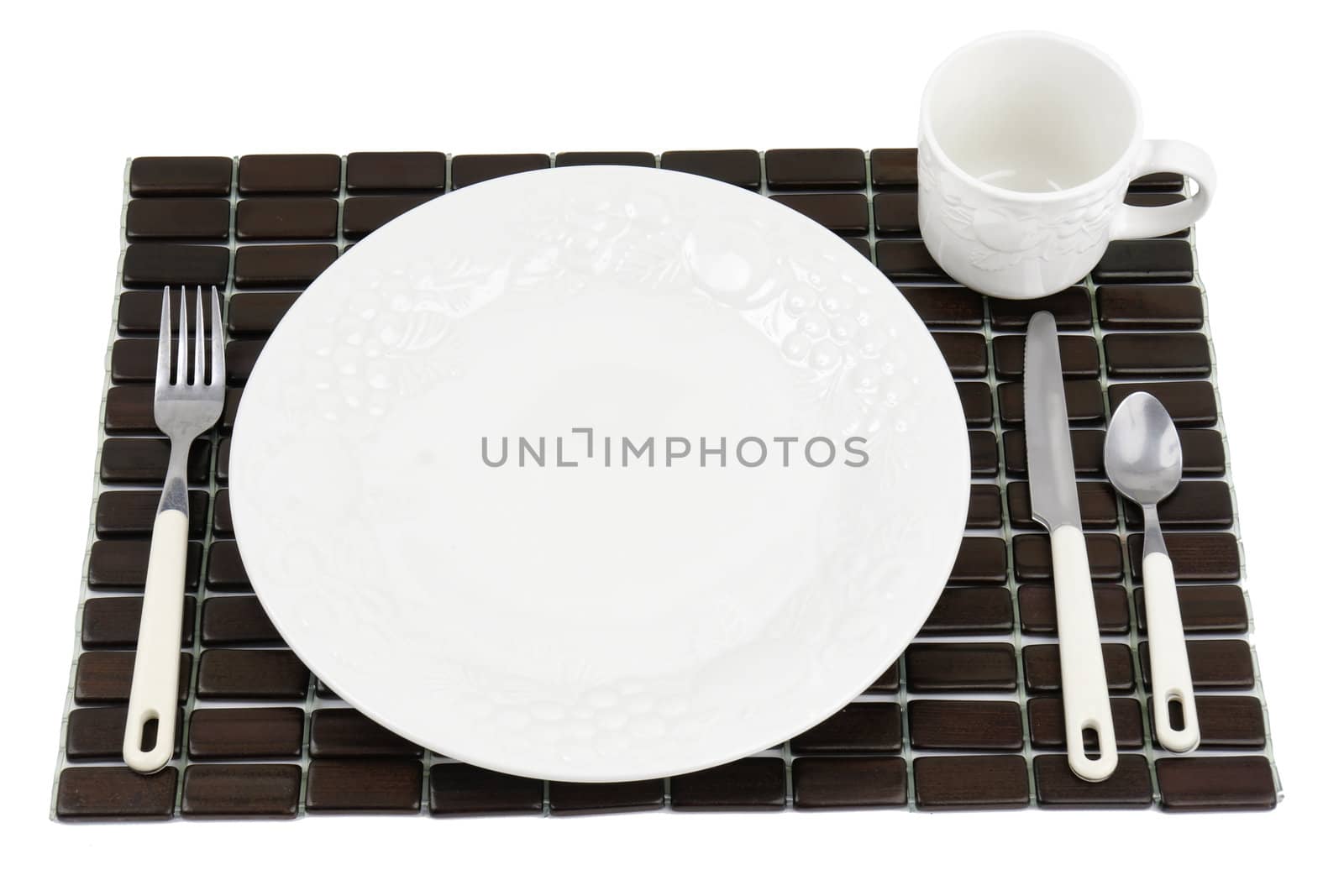 Dinner plate, white textured China with grapes and tomatoes design over a dark wood place mat.