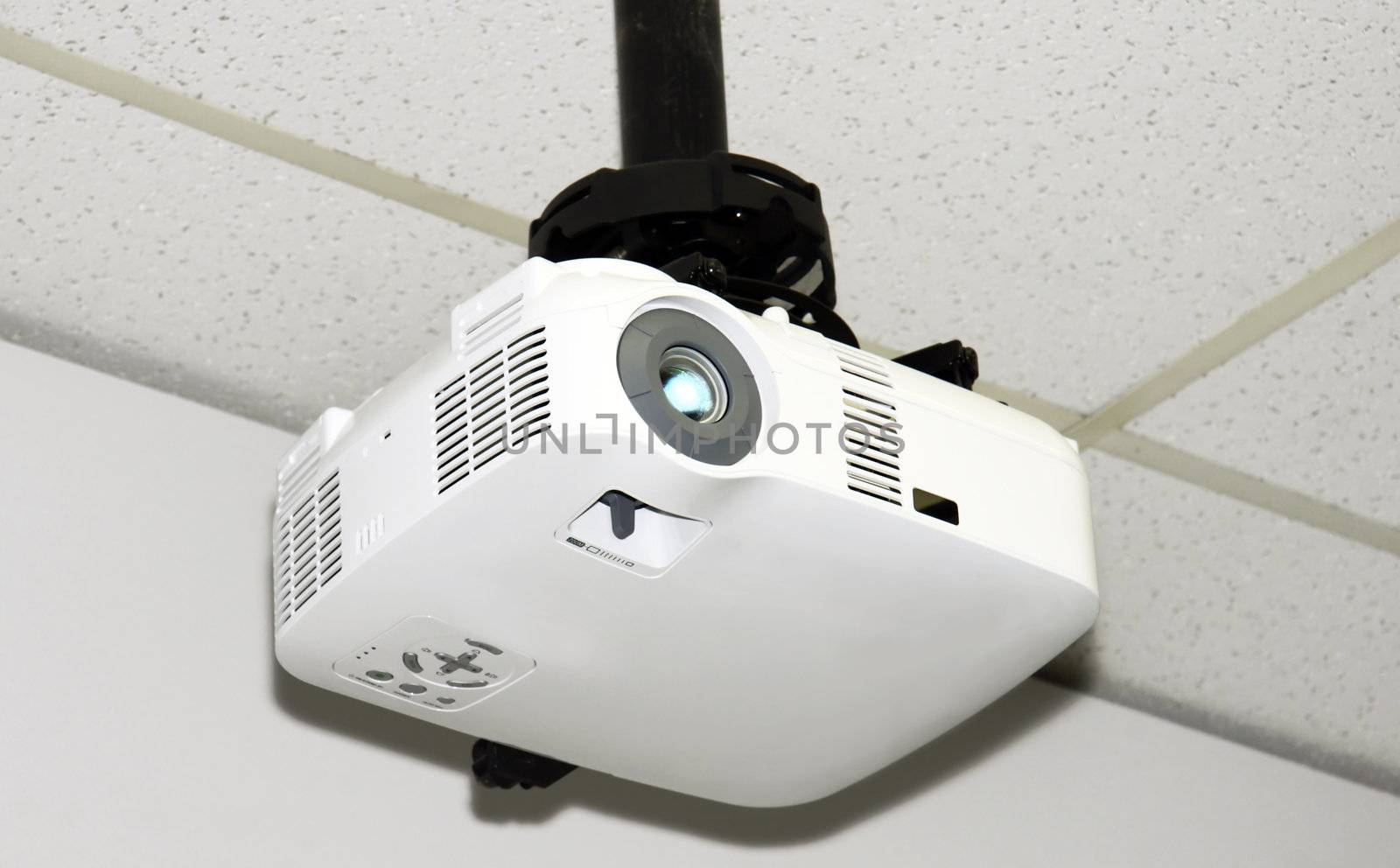 Close-up of a multi-media projector attached to the acoustic ceiling tiles of a small office.