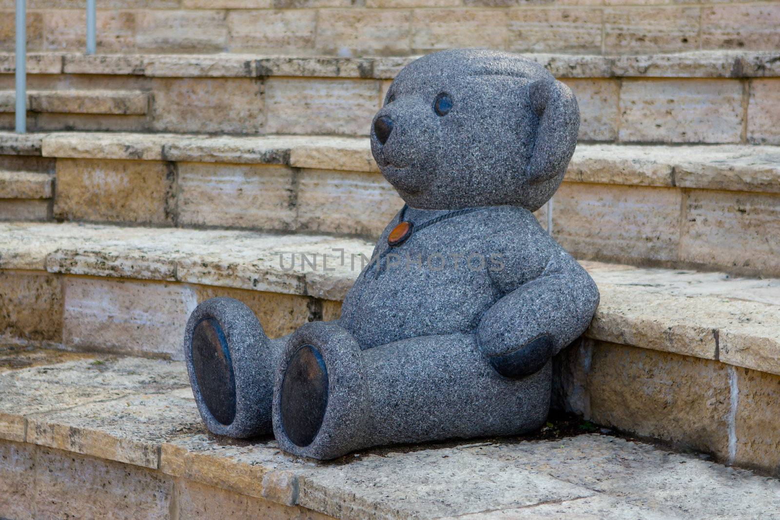 Marble statue of a Teddy Bear in a play area.