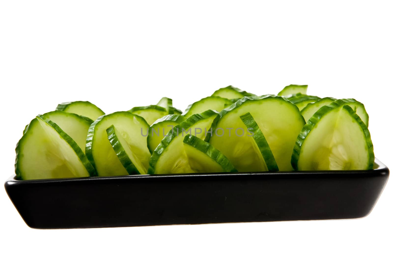 Sliced cucumber stacked on a black plate by Stootsy