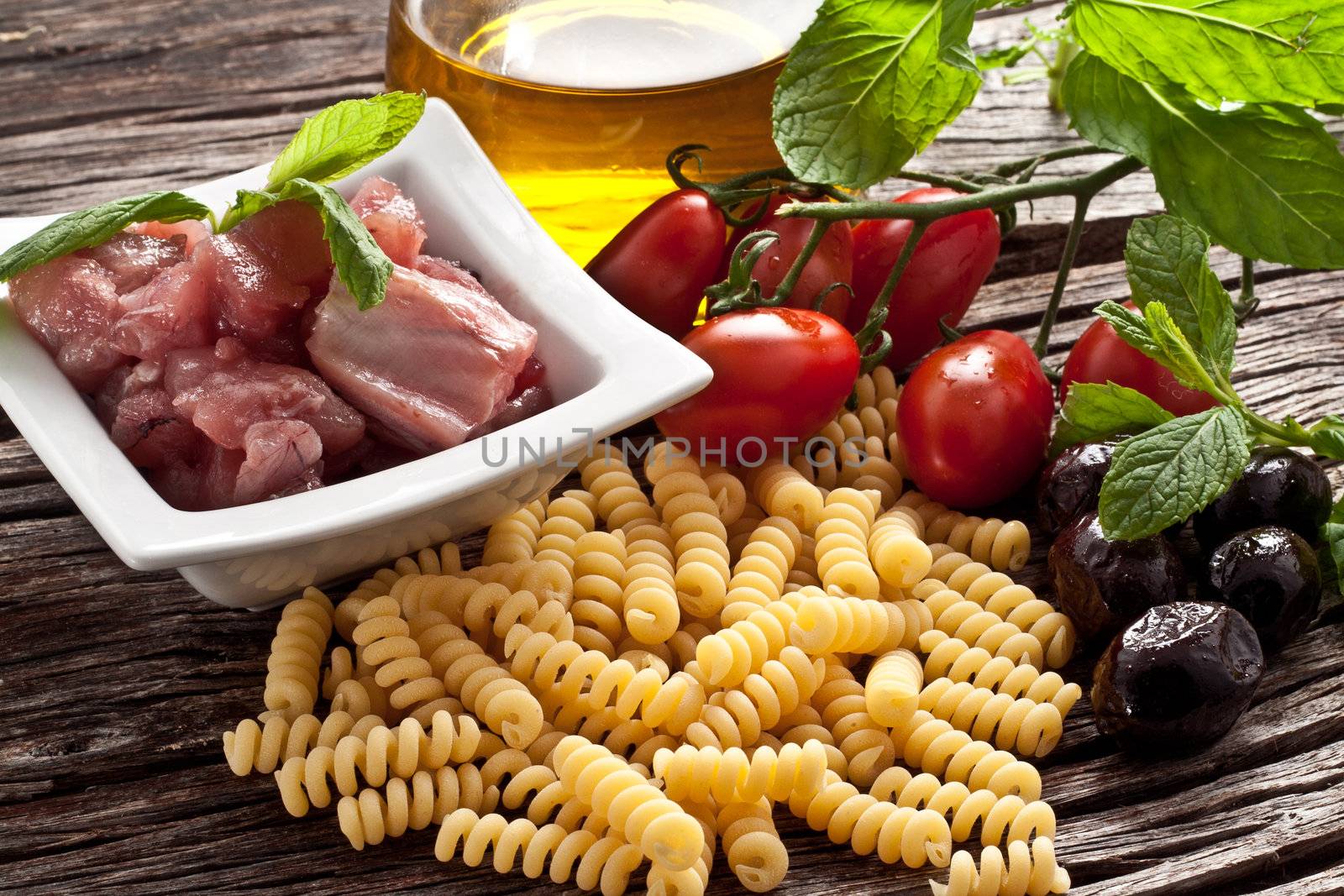 Italian Fusilli pasta with swordfish, olive and raw tomato ingredients