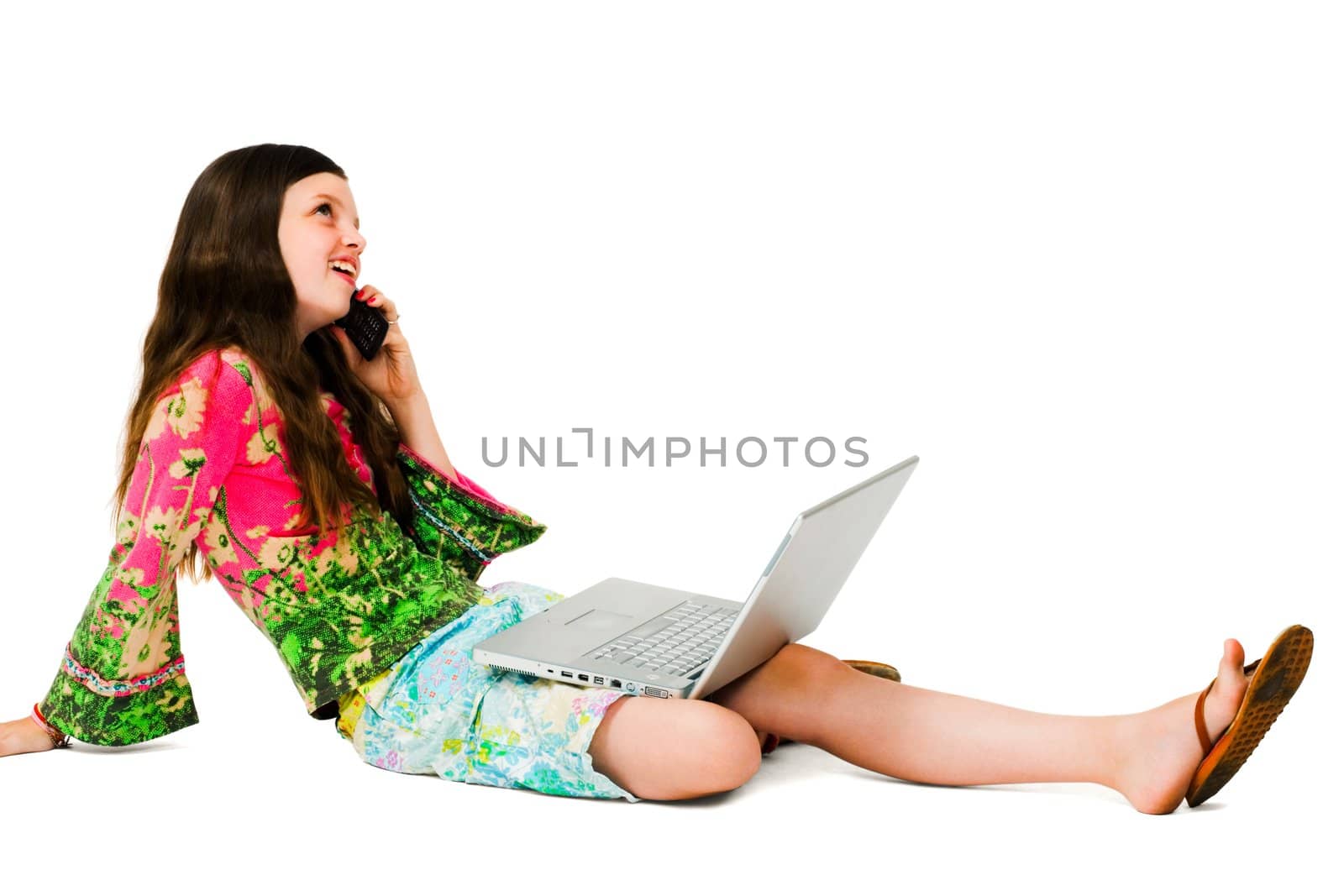 Smiling girl using a laptop and a mobile isolated over white