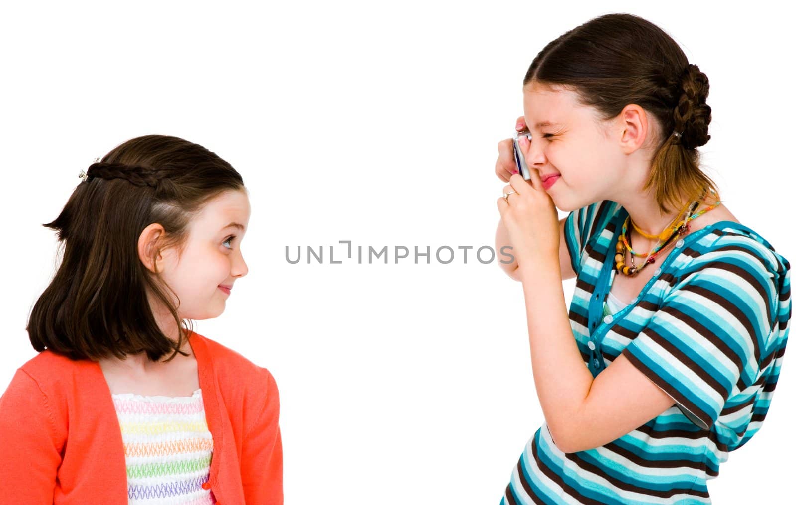 Happy girl taking picture of her sister with a camera isolated over white