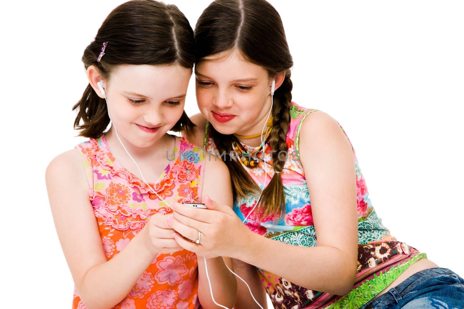 Sisters listening to MP3 player and smiling isolated over white