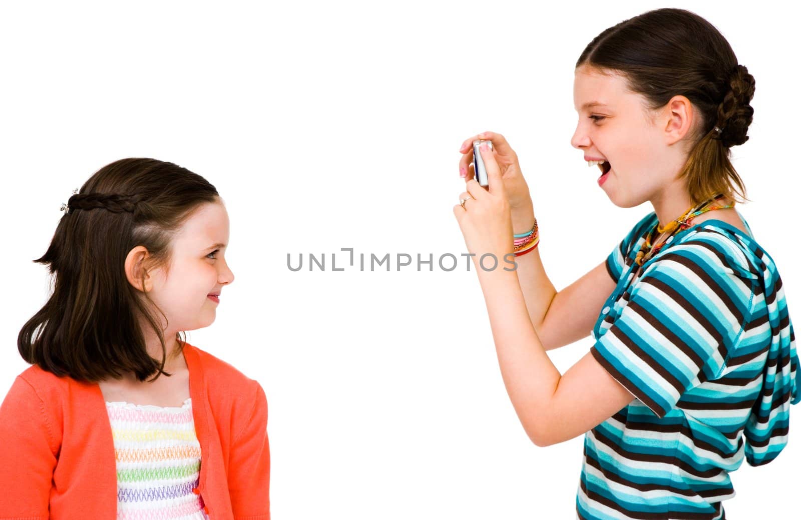 Girl taking picture of her sister with a camera isolated over white