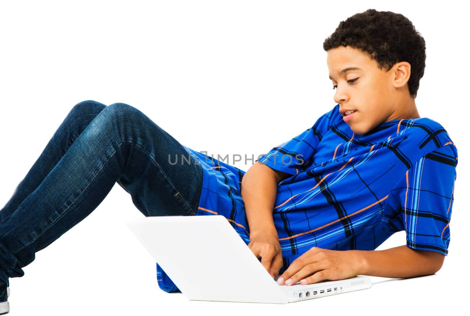 Teenage boy reclining on the floor and using a laptop isolated over white