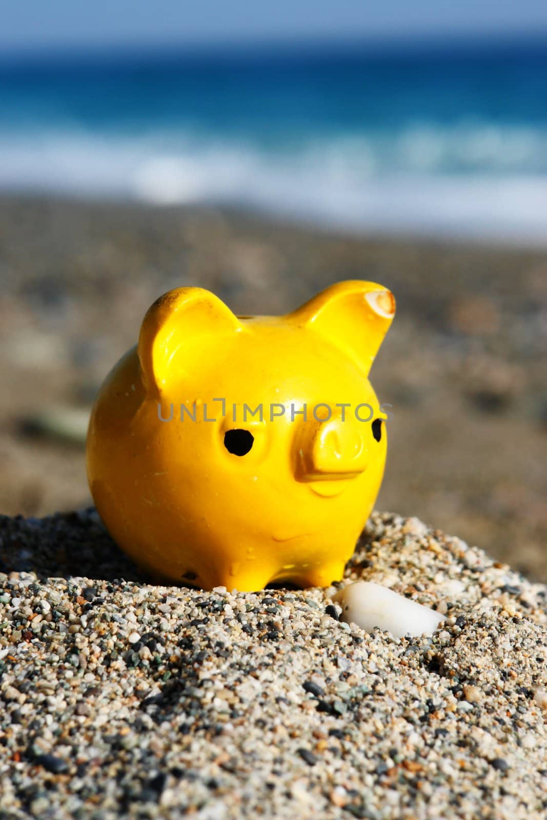 close up of a yellow piggybank on the beach