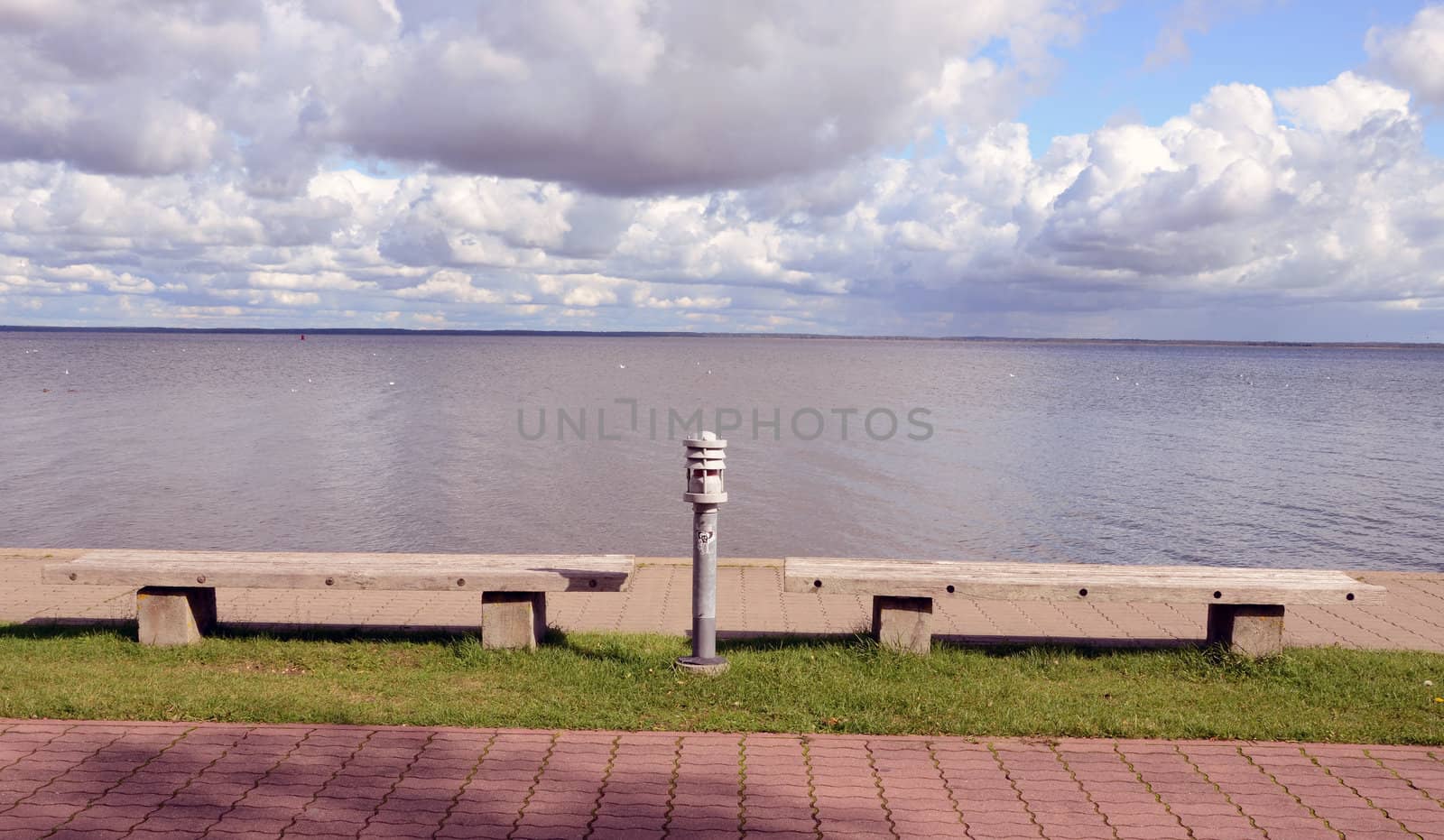 Benches and lighting in front of the lake and the cloudy sky. Park View.