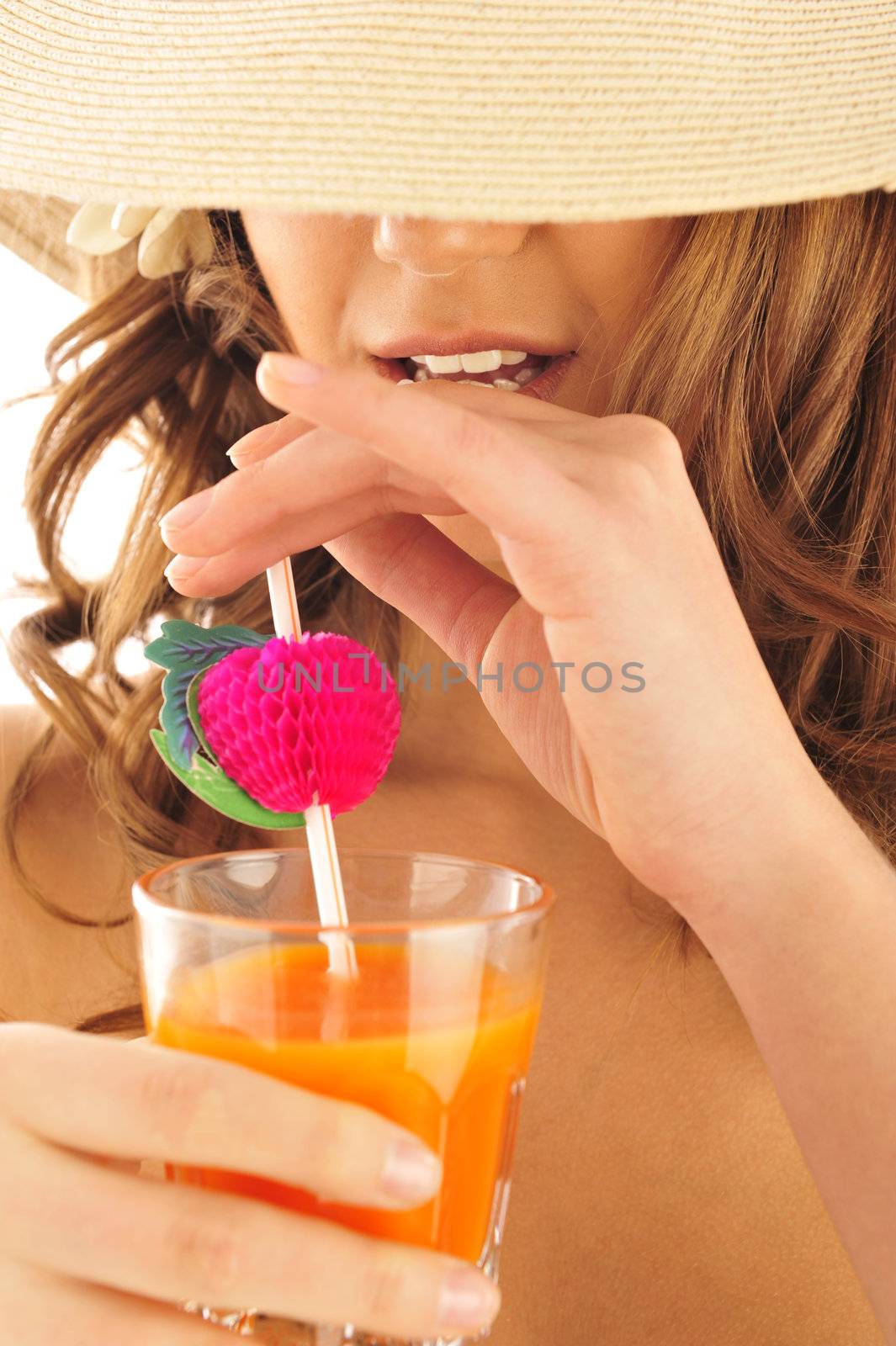 A young and sexy lady in swimsuit and hat under drinking juice on a hot day
