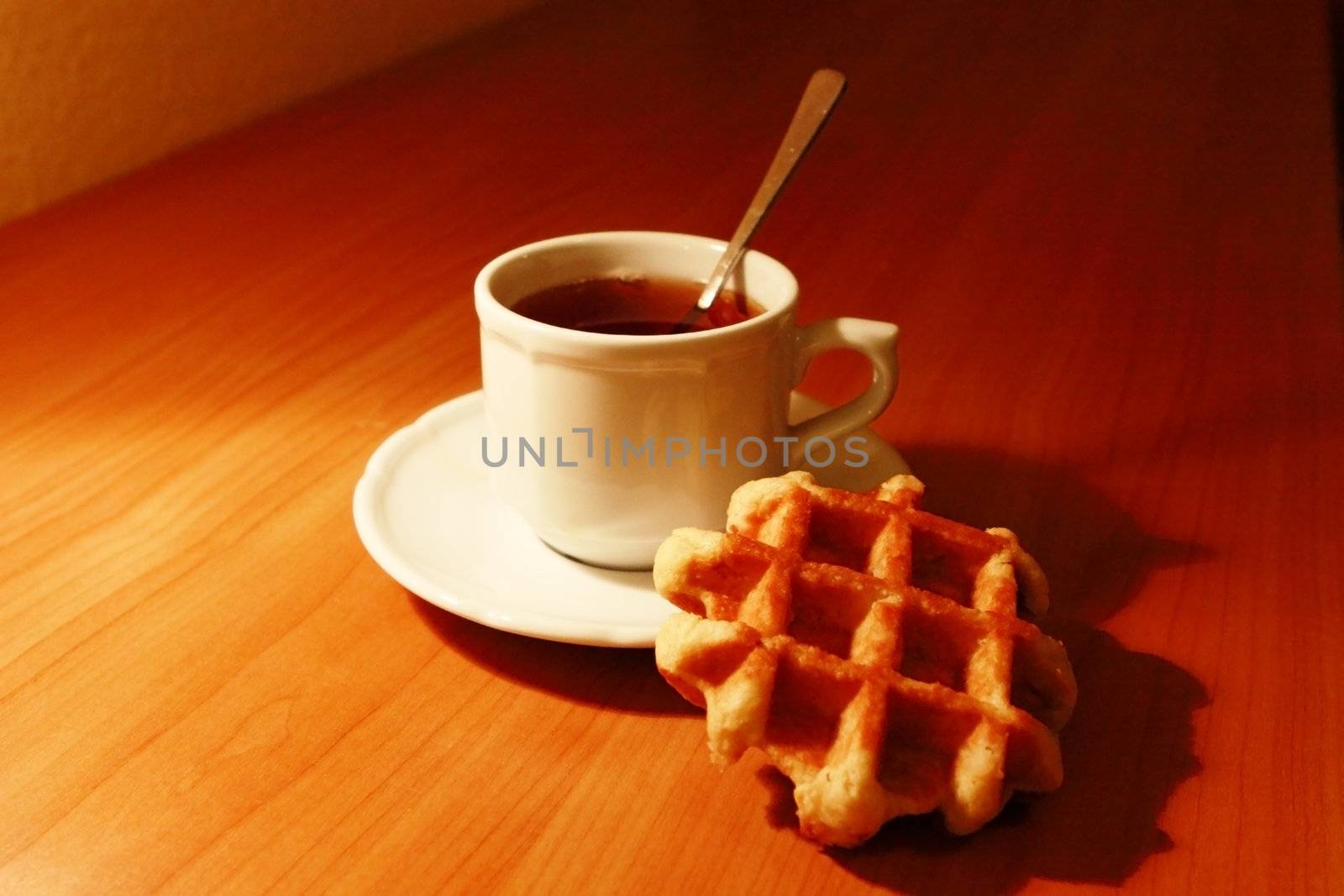 cup with hot tea and cookies with shadows