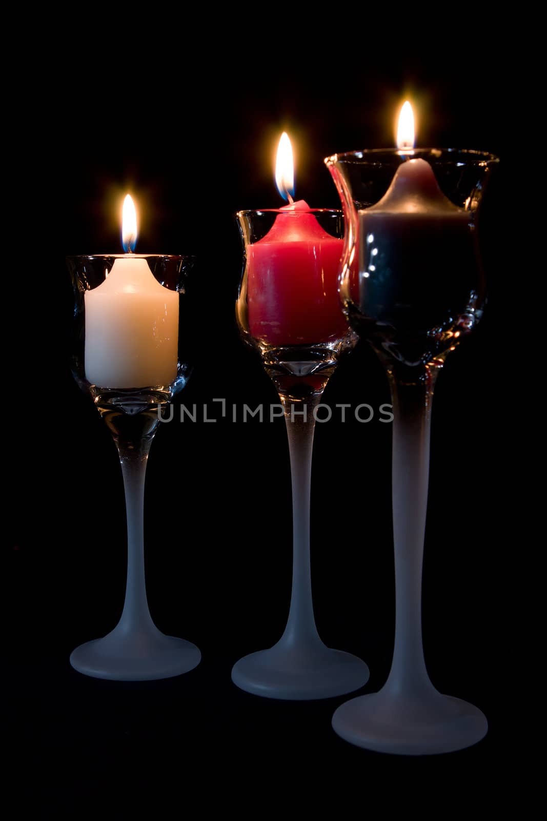 Three (3) Candles burning in decorative candle holders.