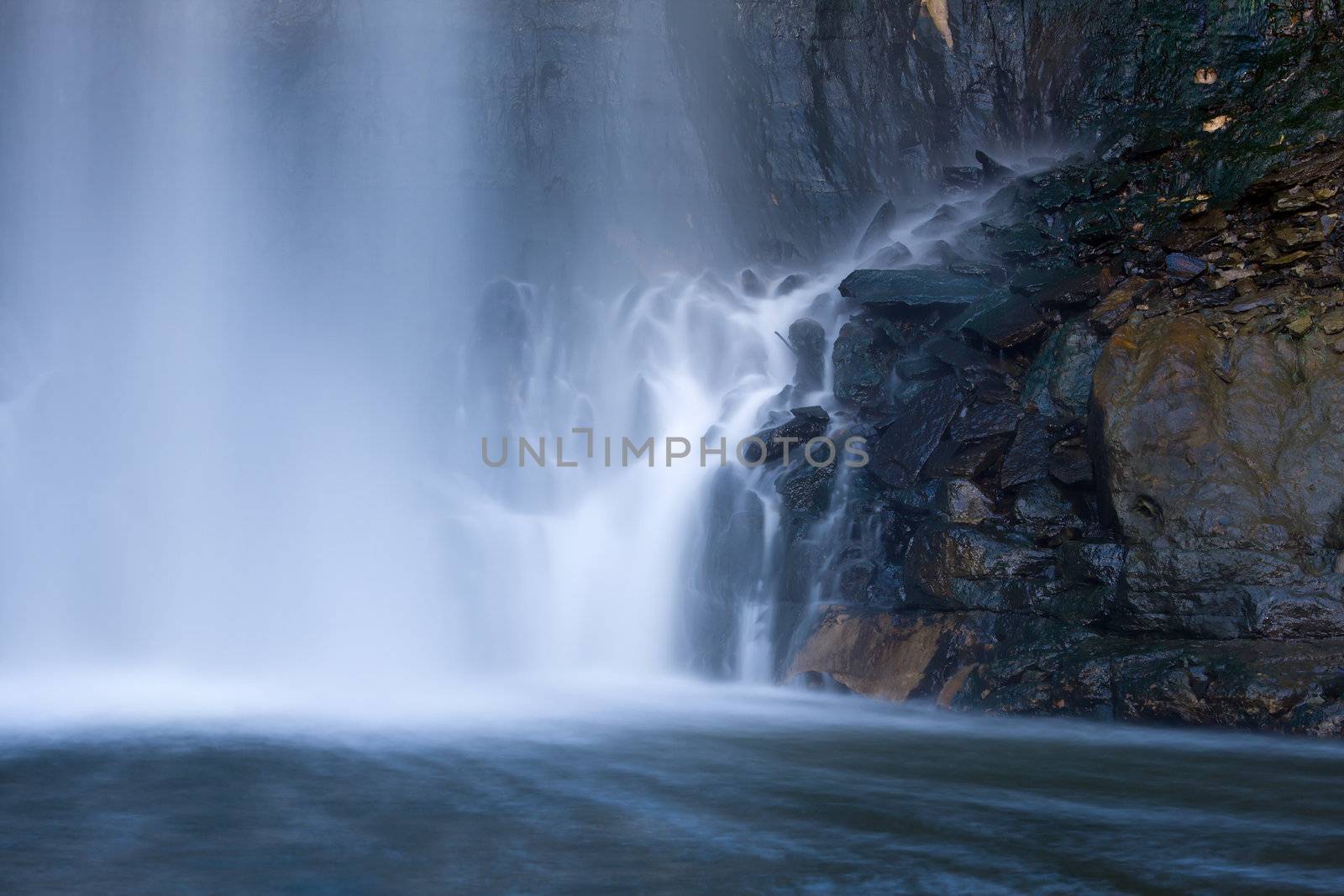 Water from a waterfall hitting the cliff wall below.