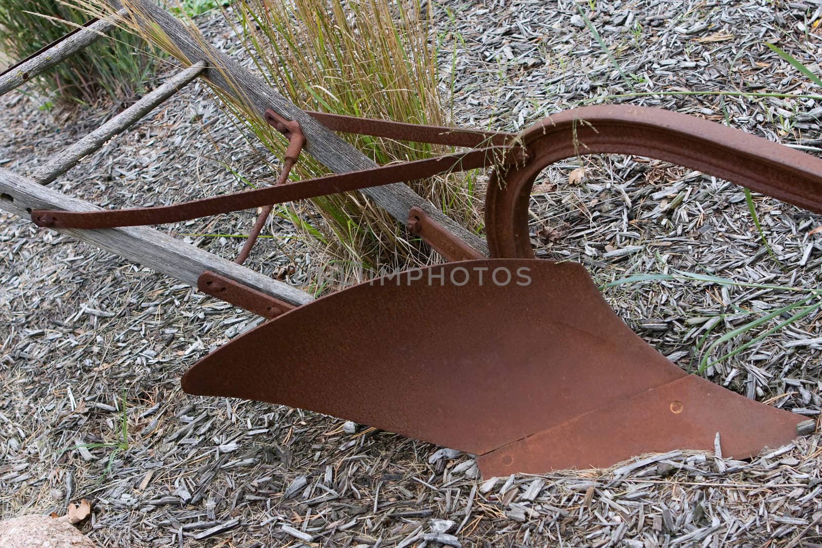 An antique plough sits quiet in the dirt.