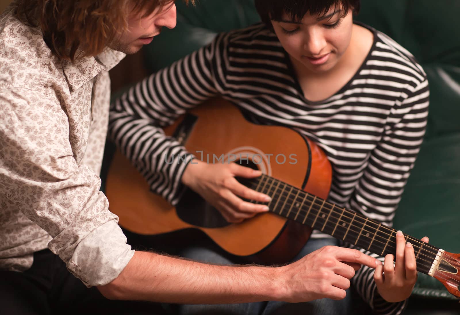 Young Male Musician Teaches Female Student How To Play the Guitar.