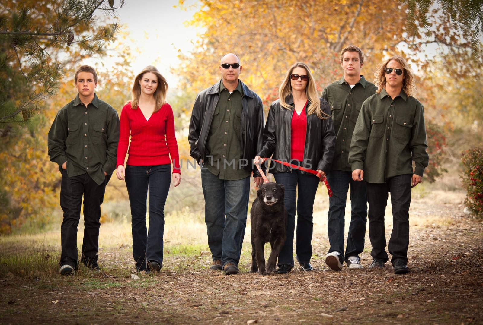 Attractive Family Portrait Walking Outdoors with Their Dog.