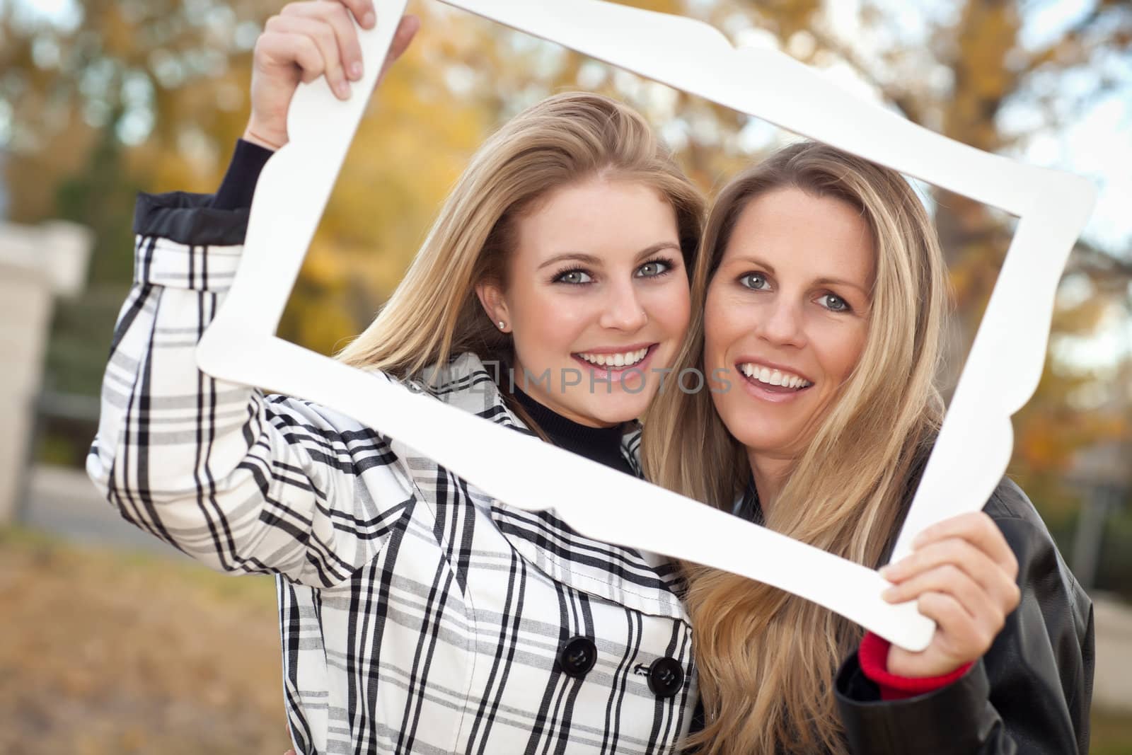 Pretty Mother and Daughter Portrait with Picture Frame in the Park on a Fall Day.