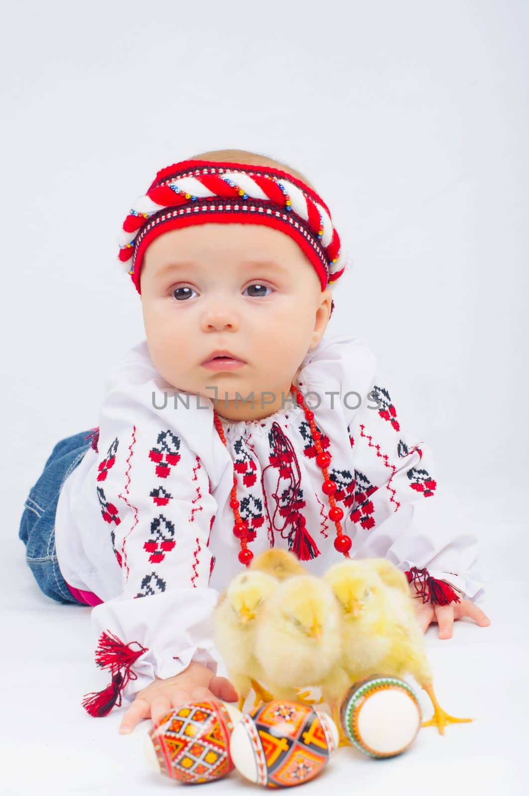 Happy little girl in the national Ukrainian costume with easter eggs and baby chickens in stusio