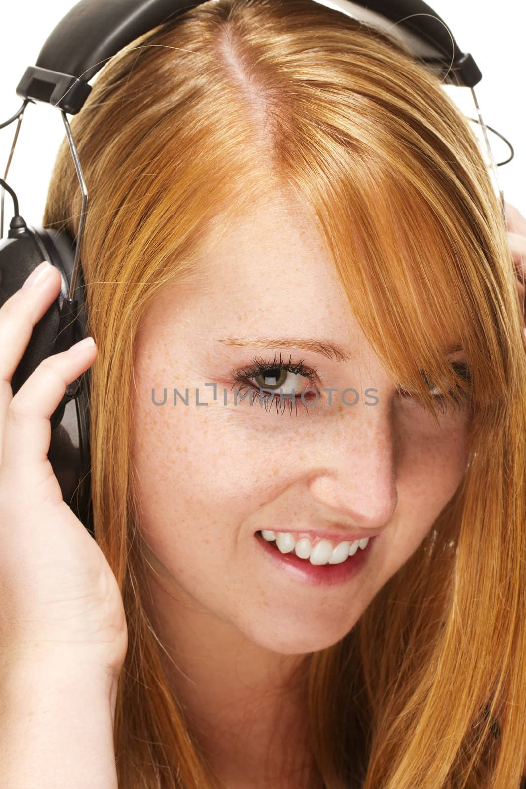 young redhead woman listening to music on white background