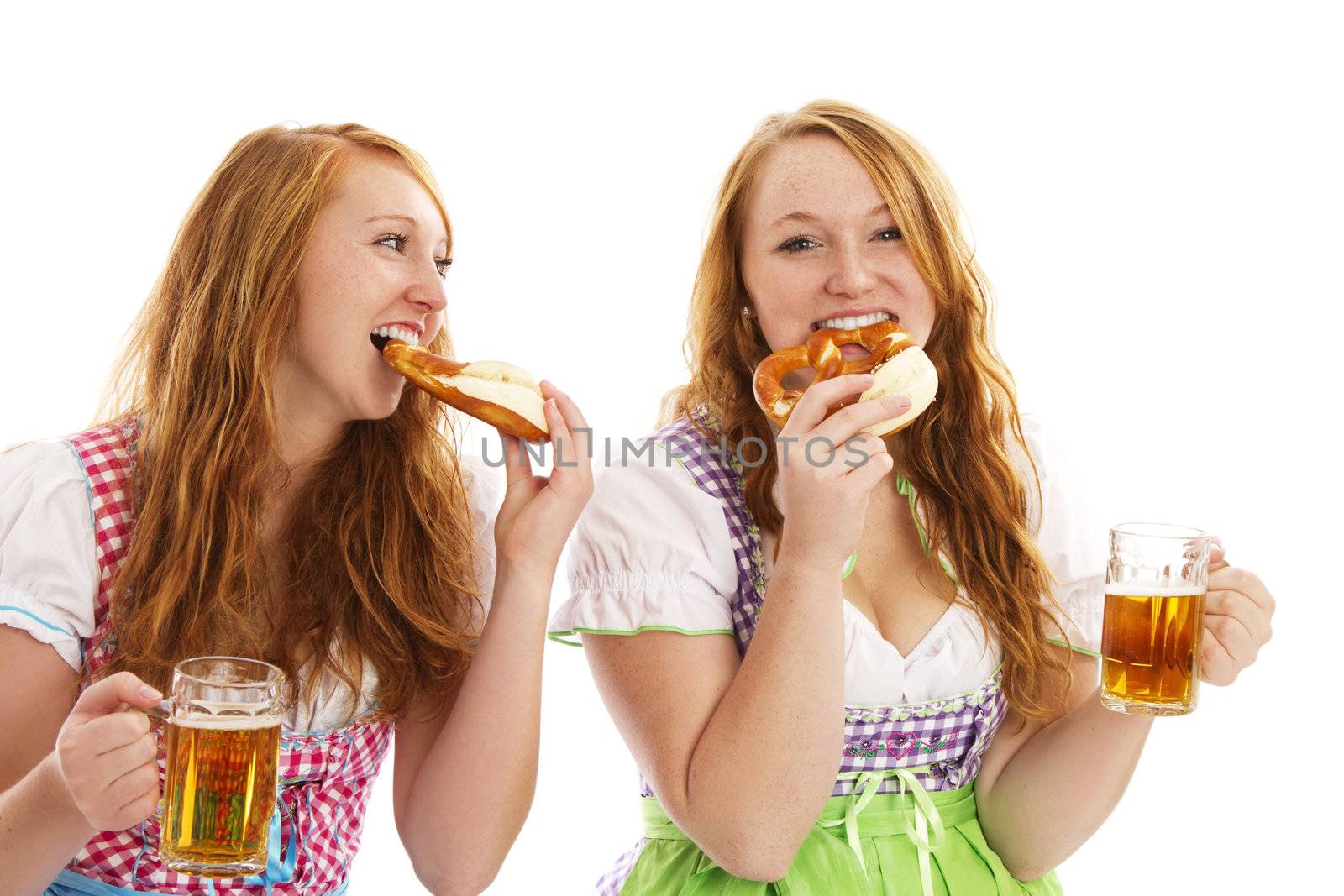 two bavarian women eating pretzels and holding beer on white background