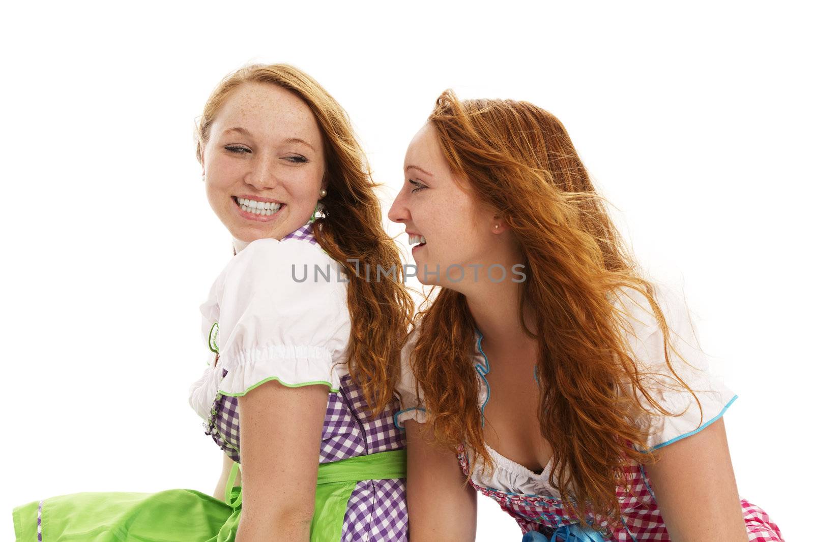 two happy bavarian dressed women looking at each other on white background