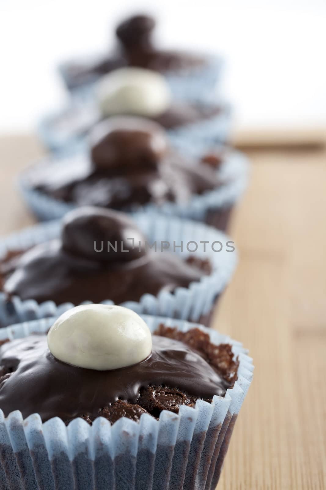 Row of chocolate cupcakes topped with candy.