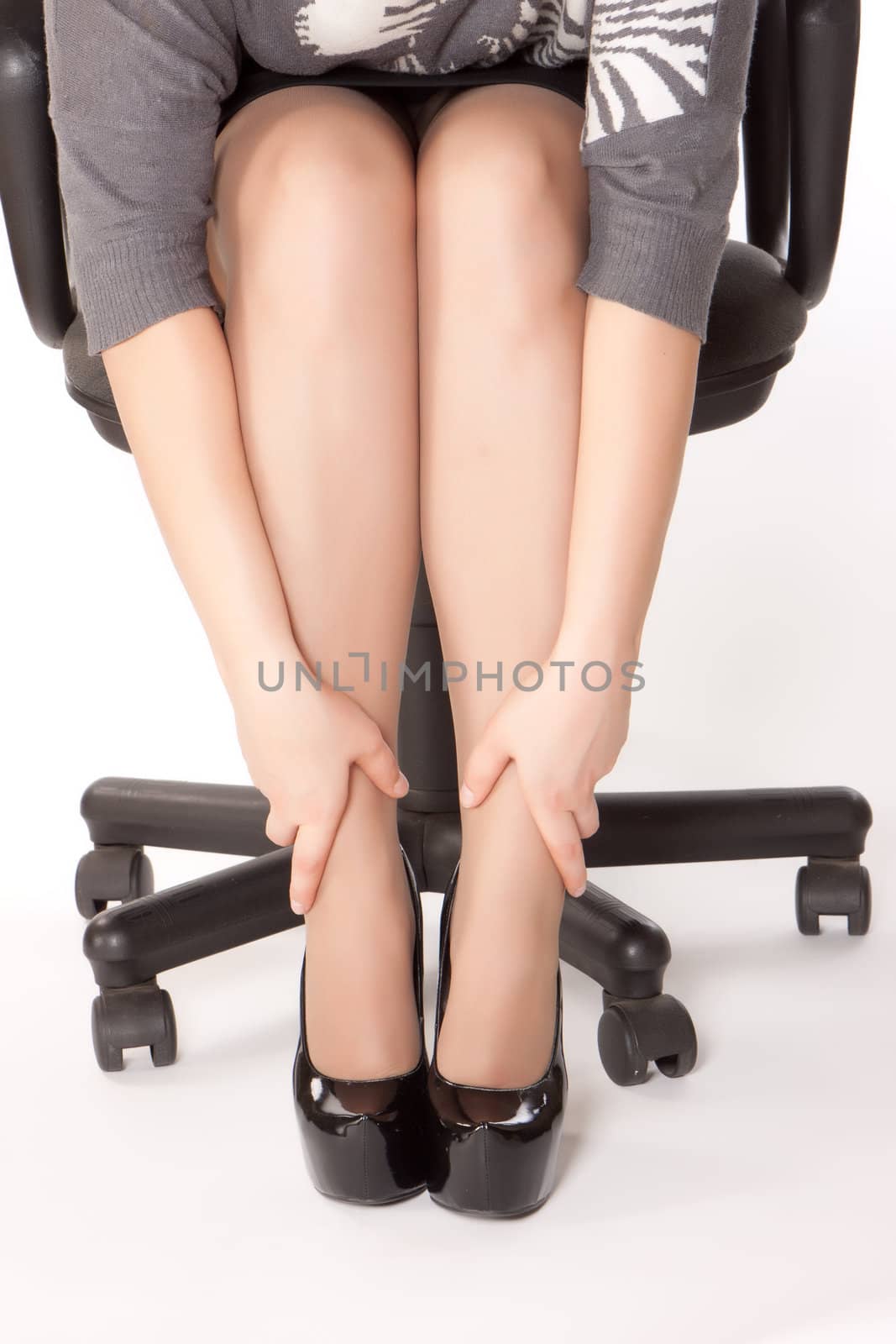 woman is sitting in chair and massaging her tired of shoes legs