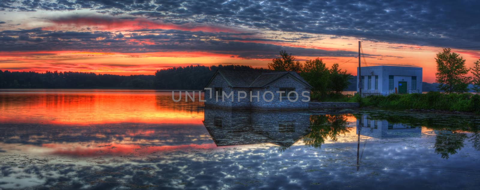 Panorama of a pump house utility and sunrise on a lake.