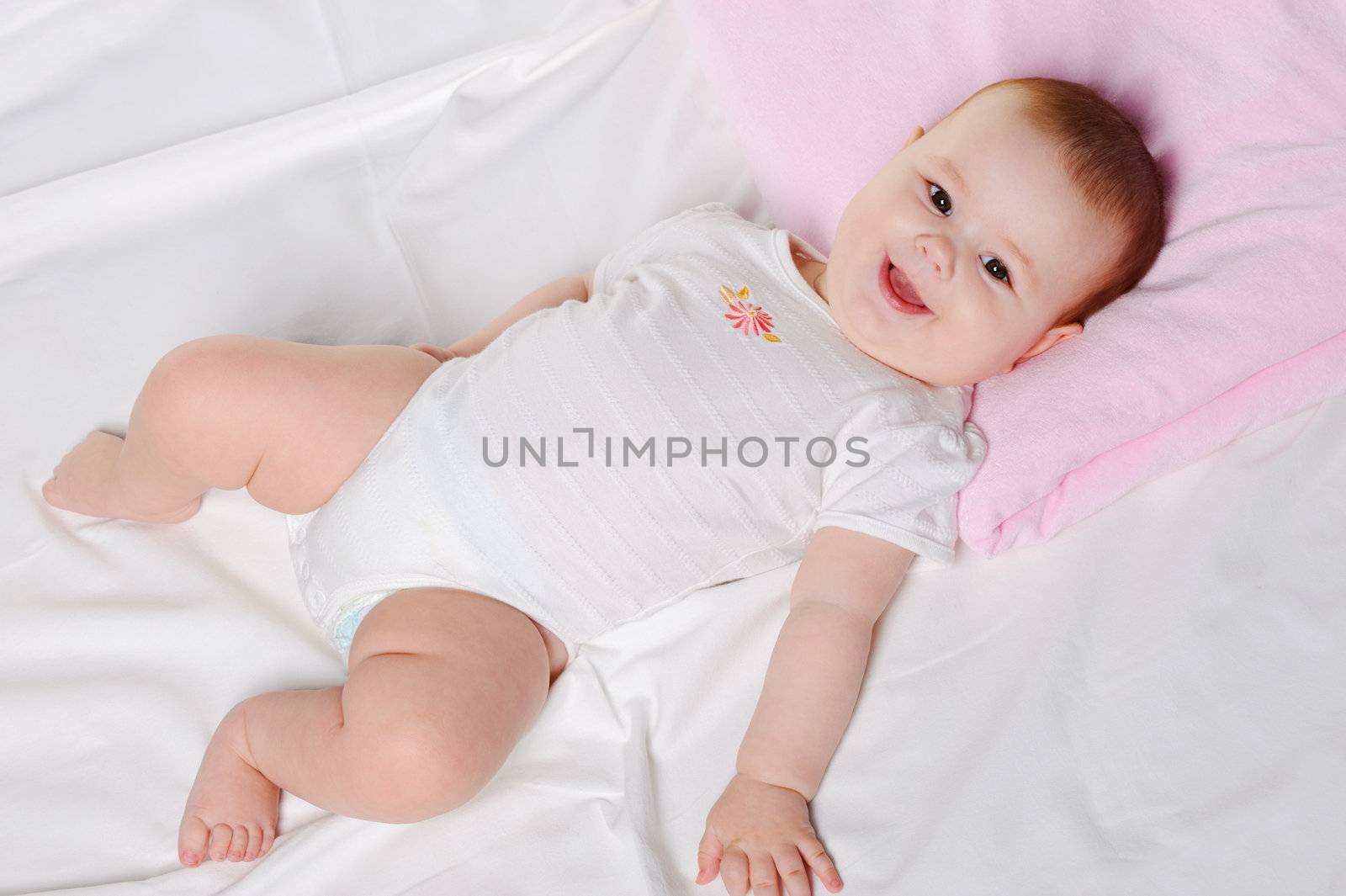 The baby lays. Age of 8 months. It is isolated on a white background