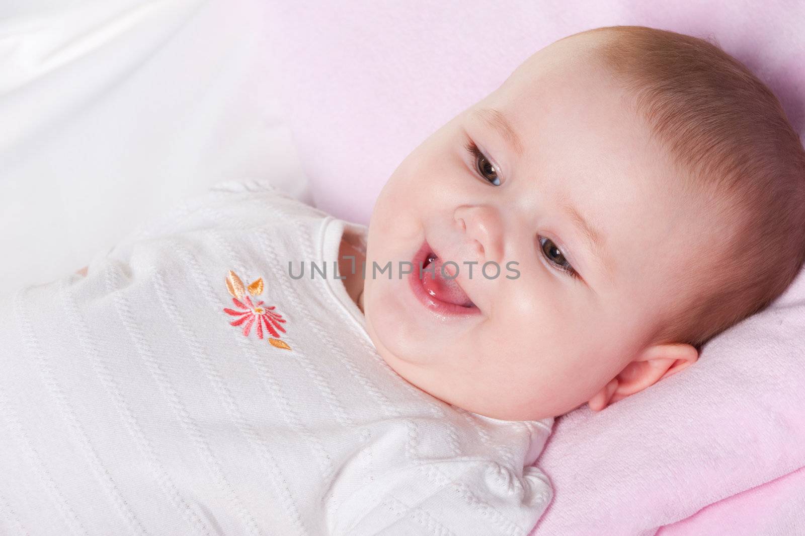 The baby lays. Age of 8 months. It is isolated on a white background