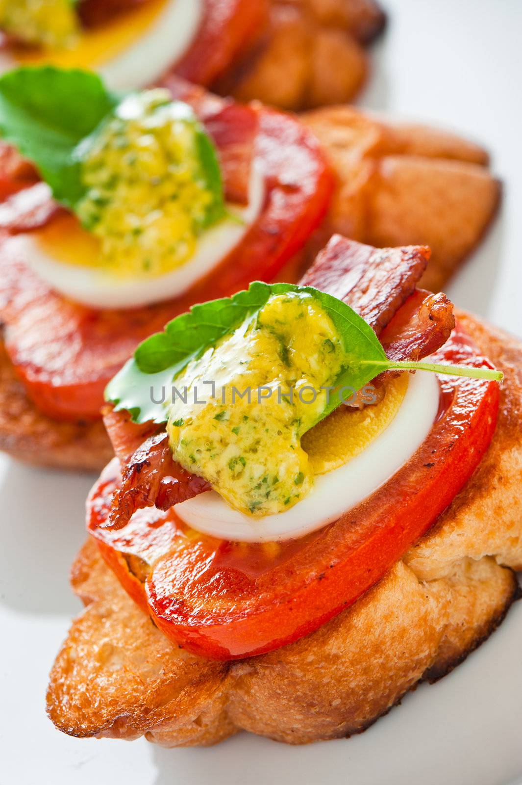 A baguette slice with tomato egg bacon and herb butter
