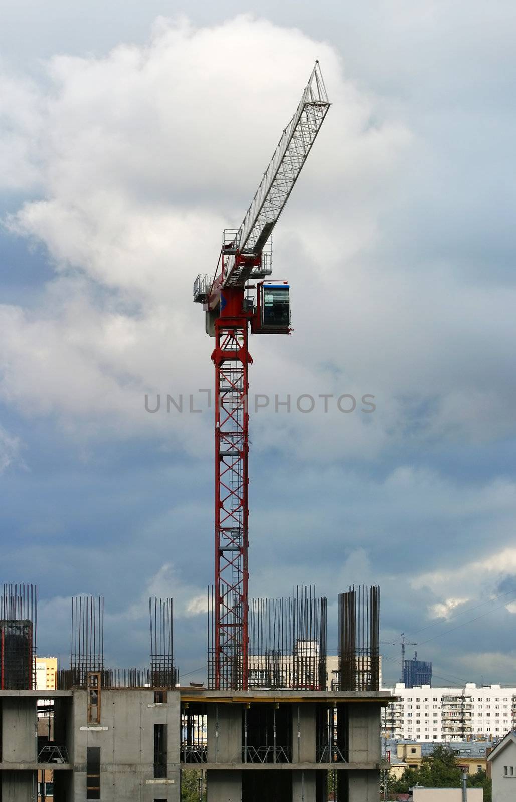 The building crane on a background of the sky and the unfinished building