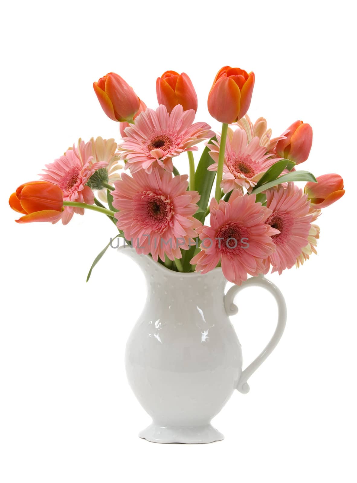 A bouquet of daisy gerberas and tulips in a beautiful pitcher vase