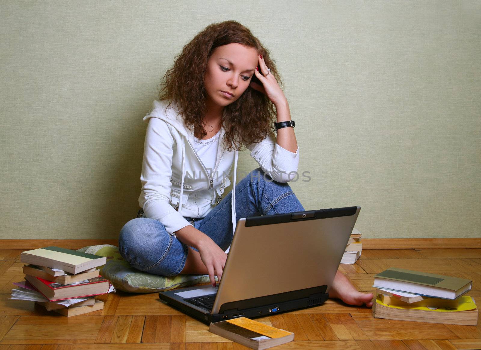 The young girl among books with a computer