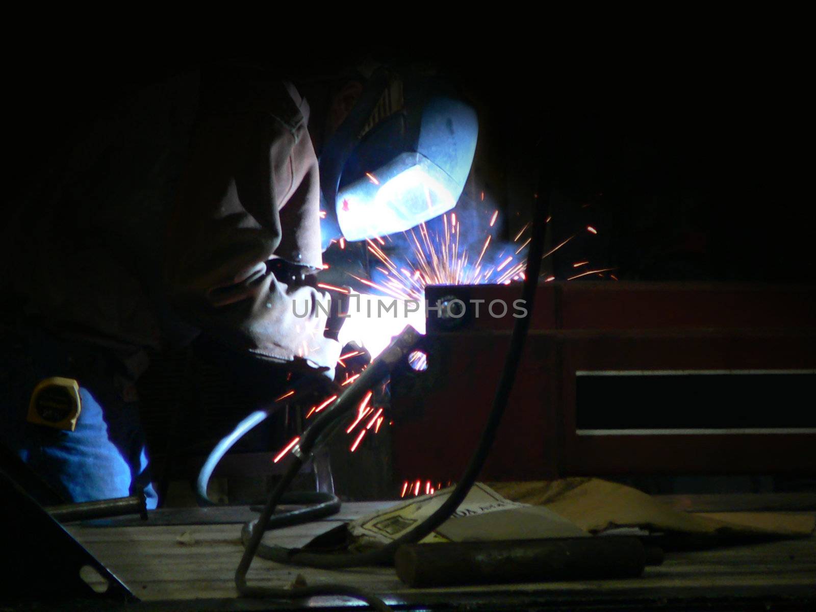 A man welding a piece of farm equipment.