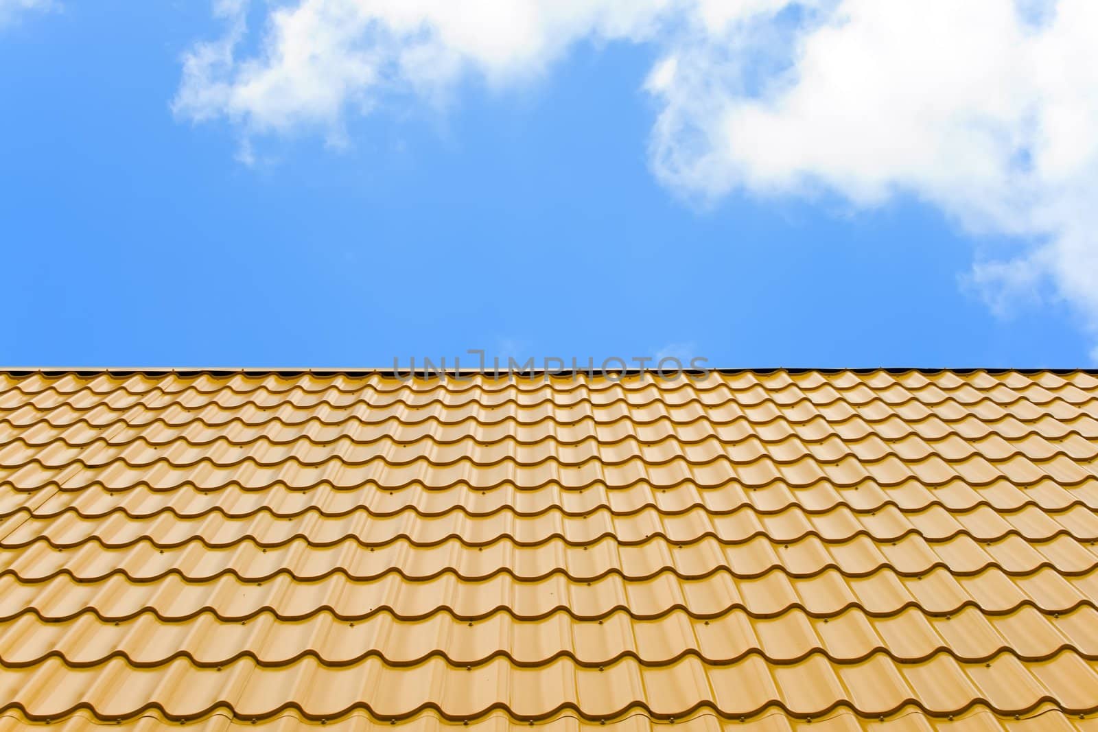 a roof is covered a yellow wavy metal on a background blue sky with white clouds