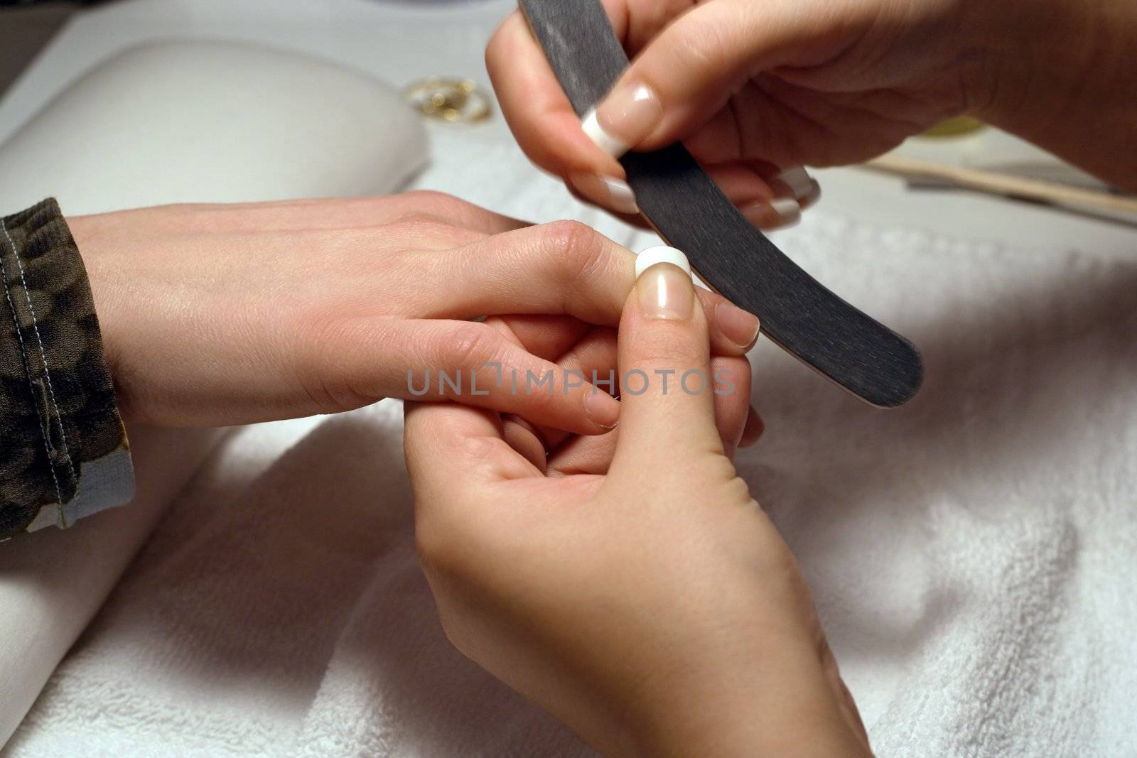 A manicurist filing the fingernails during a manicure.