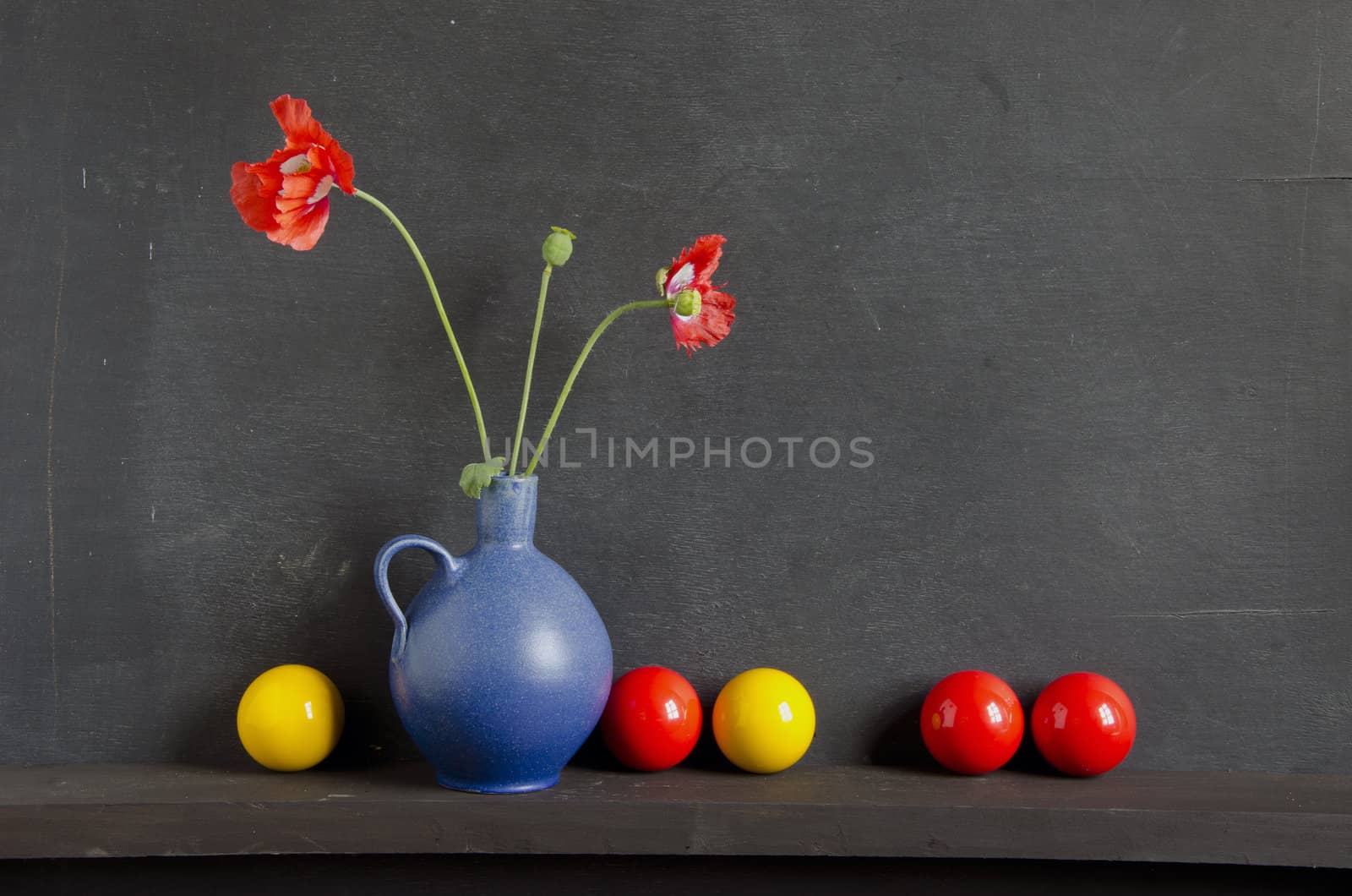 still-life with poppy and colorful balls on black background
