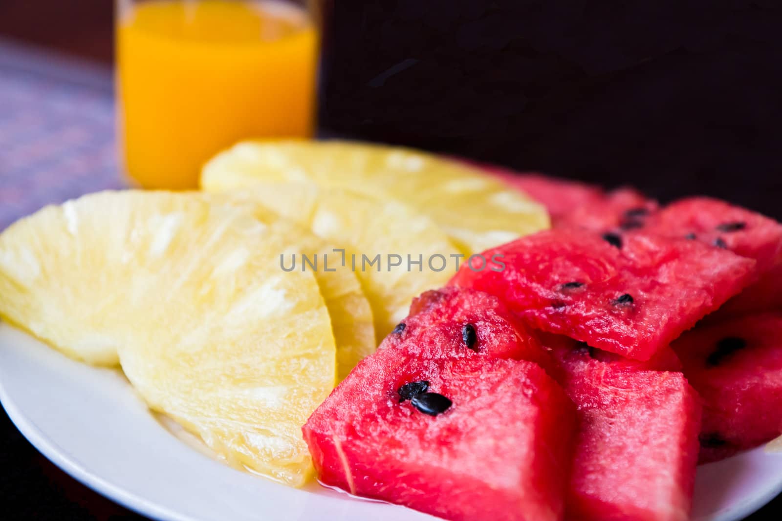 Orange juice and fruit in the dish on the dining table.