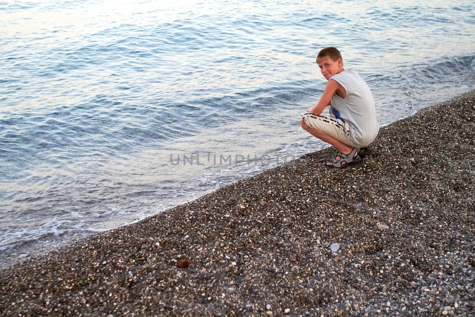 youth sits in summer on the shore sea