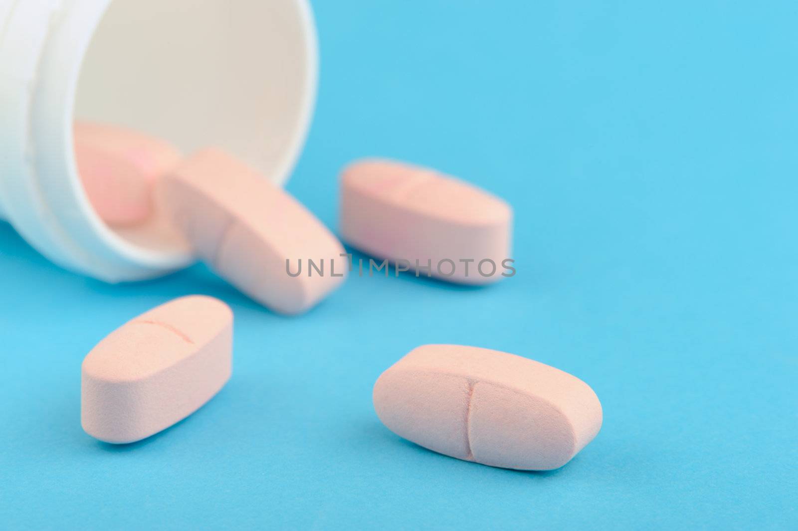 Pink tablets in white plastic packing. A blue background