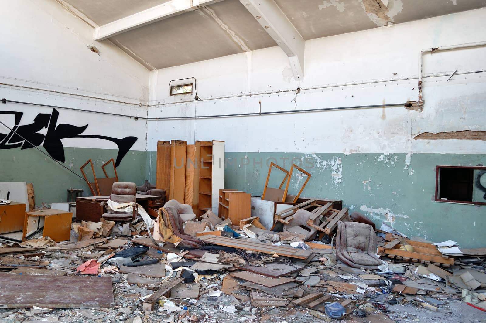 Vandalized office equipment and debris in a partially demolished abandoned factory.