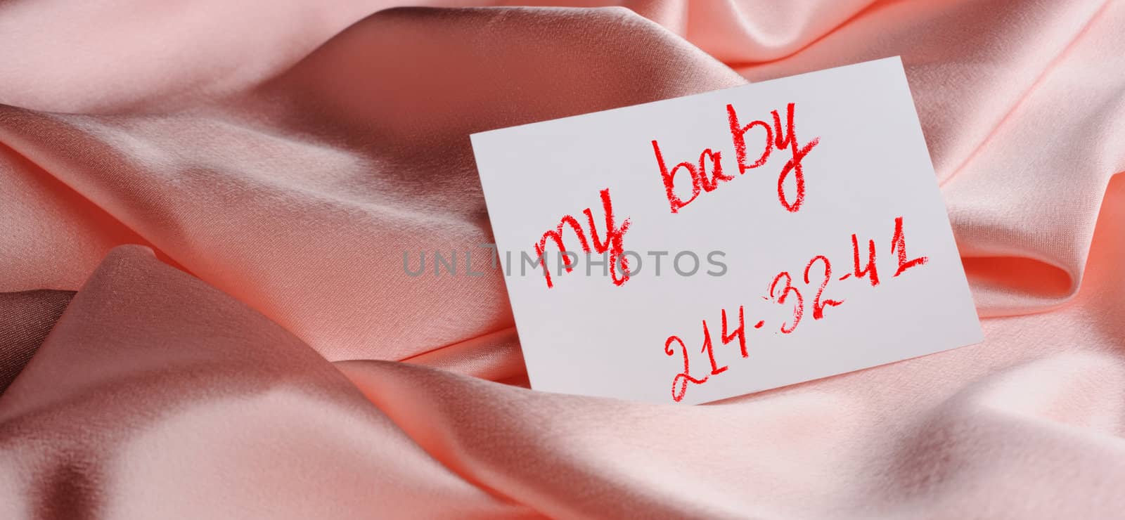 Note on beige silk. With an inscription " My baby " and an invented phone number. Drawn by lipstick