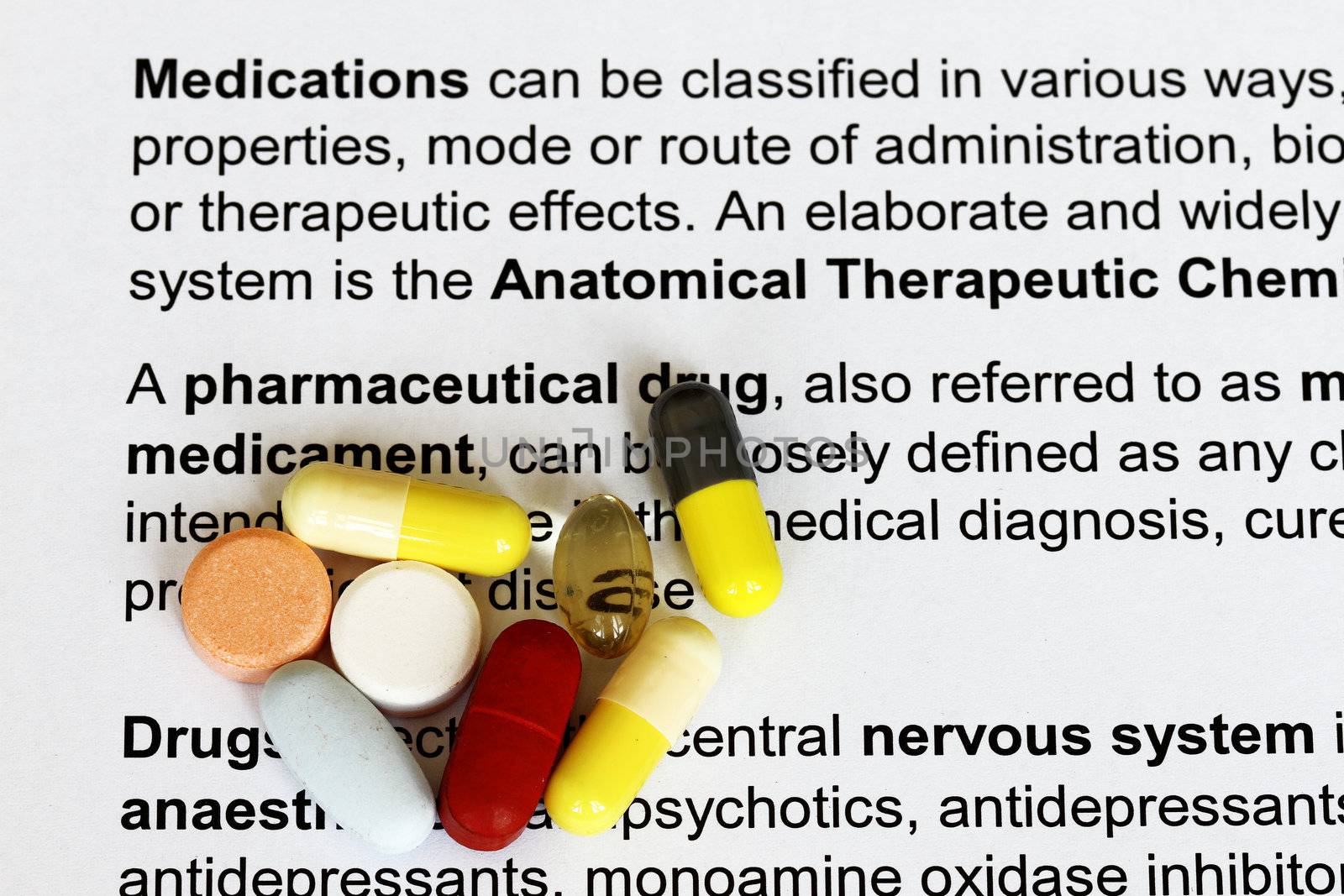 Drugs capsules and pills on a lying on a medical document.