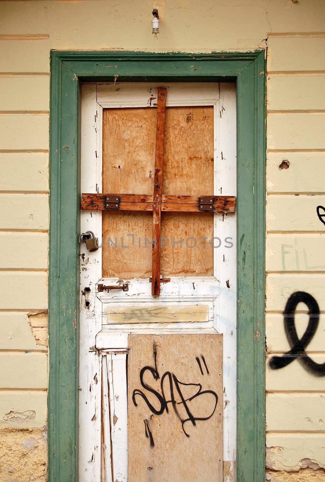 Boarded up door and weathered wall surface of an abandoned house.