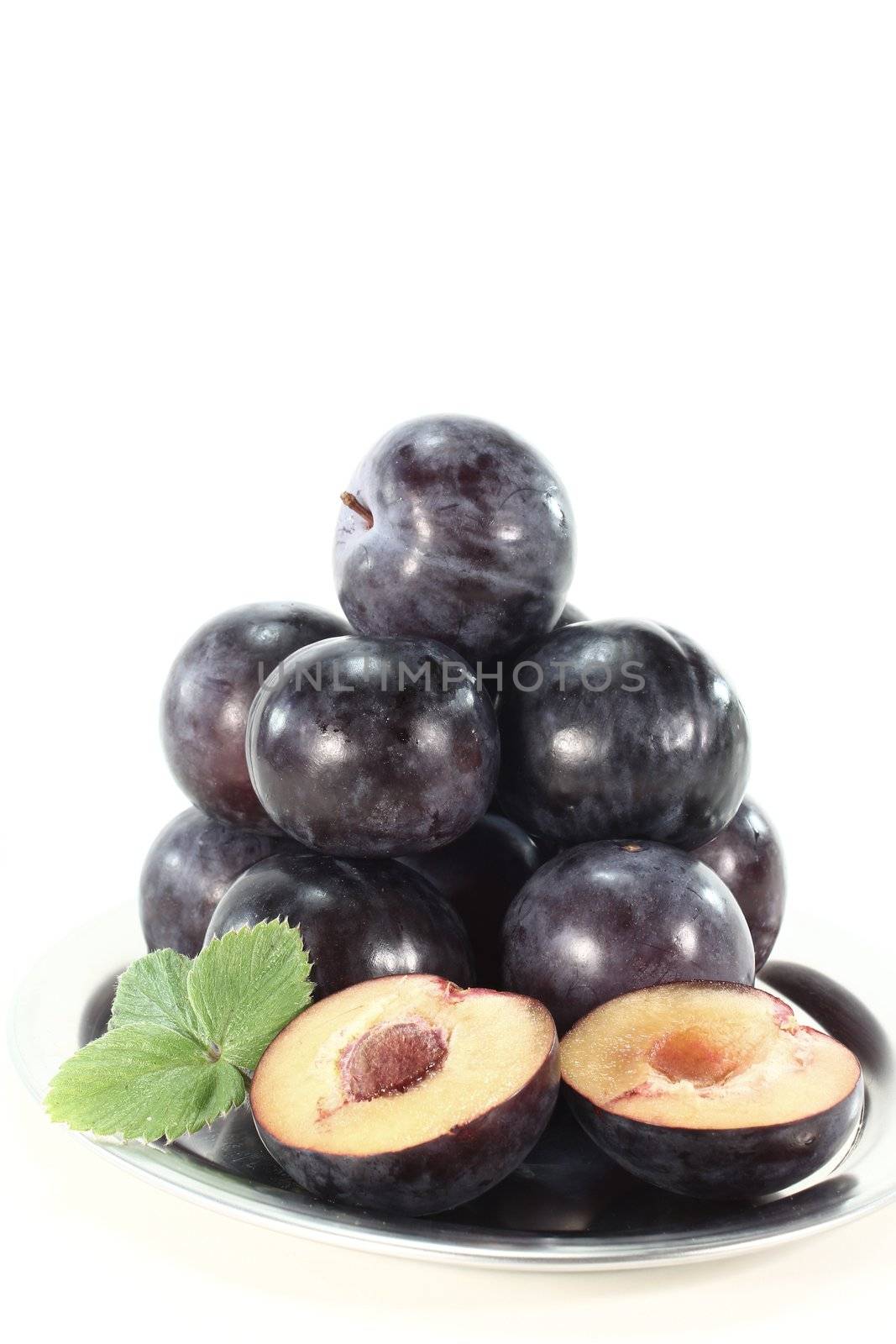 Fresh plums with leaves on a silver platter