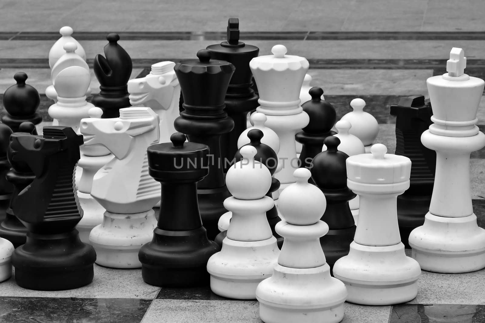 Lifesize chess pieces and checkered pattern floor tiles. Black and white.